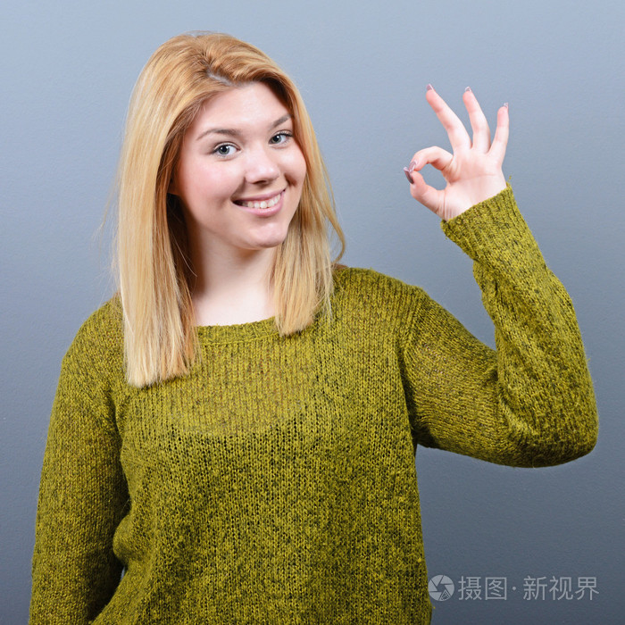 幸福的女人,显示 ok 的手势,在灰色背景下的肖像