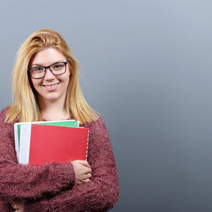 快乐的学生女人拿着书与反对大拇指的肖像