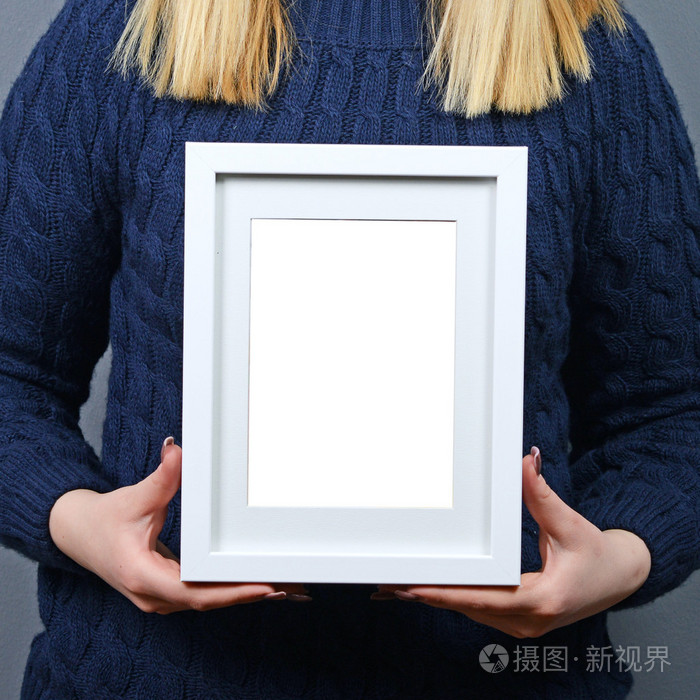 微笑的女人控股空白相框反对灰色的肖像