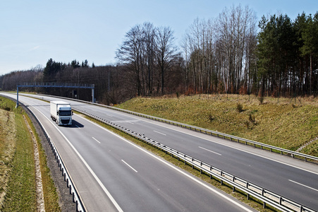 在早春树林周围的高速公路。根据电子收费站的白色卡车