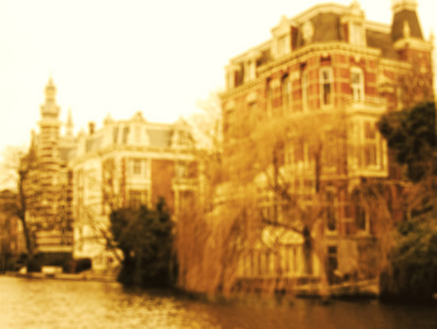 阿姆斯特丹的房子和垂柳运河在多云的日子。模糊的健美的照片。阿姆斯特丹的房子和垂柳运河在多云的日子。模糊的健美的照片