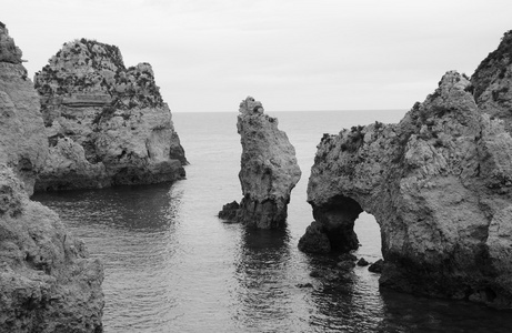 在傍晚的灯光下, 多纳安娜海滩 葡萄牙阿尔加维海岸拉各斯 的石头拱门洞穴岩层。旧照片。黑色和白色