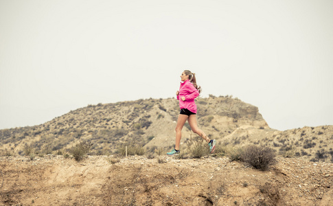 年轻的运动女人逃跑的线索脏路与干燥的沙漠地貌背景训练刻苦