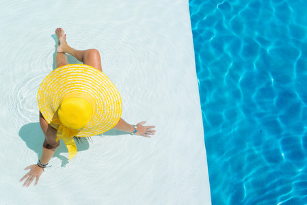 女人在游泳池里戴一顶大帽子放松
