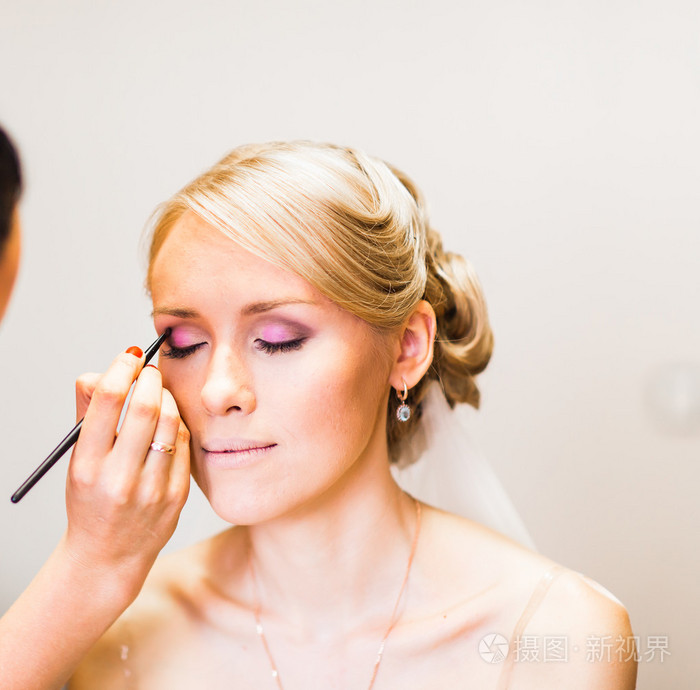 化妆师正在化妆年轻美丽的新娘婚礼化妆准备