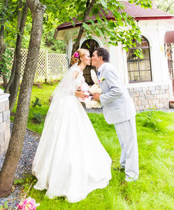 婚礼着装一束鲜花和绿叶的夫妇是在手里，新郎和新娘接吻