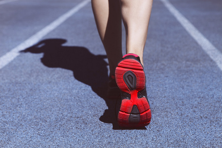 运动员赛跑者脚下来体育场跑道。在女性的鞋子的特写