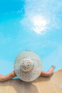 大帽放松的游泳池不可识别的女人