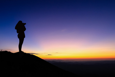 女人以剪影照片站在山顶和享受丰富多彩的天空