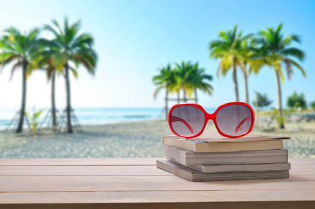 红红的太阳眼镜的书与海景背景堆栈上