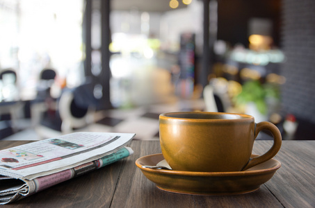 褐色的咖啡杯子和褐色的木桌上的报纸