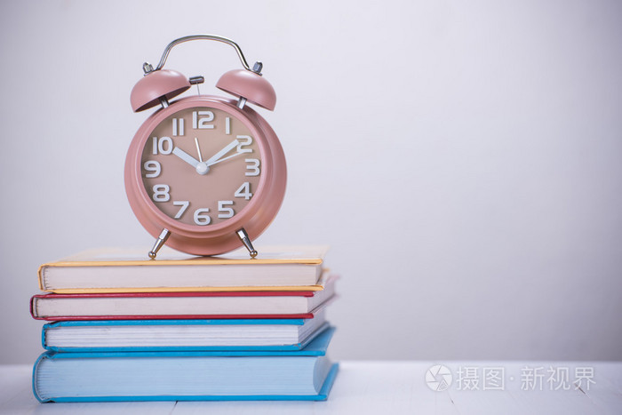 打开的书的堆栈上的闹钟