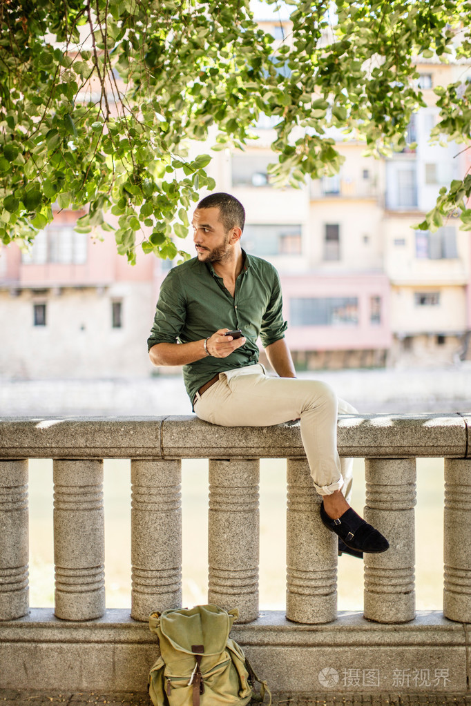 侧面图的坐在树下的篱笆上有胡子的人