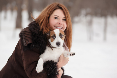 年轻的红发女子户外与可爱的小狗杰克罗素梗犬，冬季