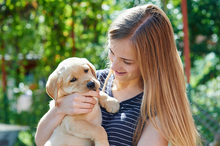 年轻女子在拉布拉多幼犬的手上捧着的肖像