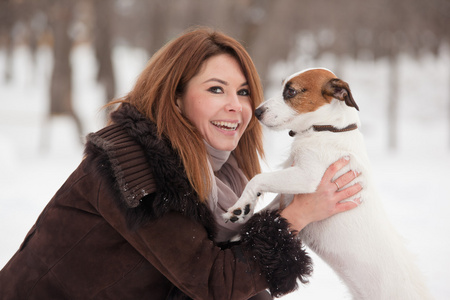 年轻的红发女子户外与可爱的小狗杰克罗素梗犬，冬季