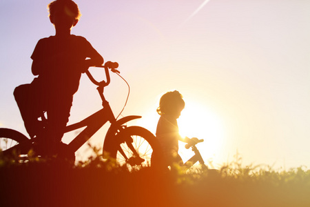 小男孩和女孩在日落时骑自行车