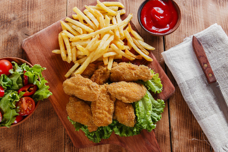 在加酱和炸薯条的面包屑炸鸡翅照片