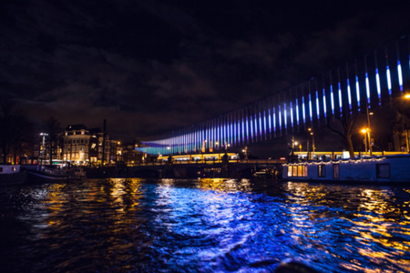 夜间照明反射在阿姆斯特丹的渠道，来自移动巡航船。作为背景的模糊抽象照片