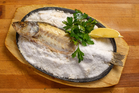 在一张木桌上的盐焗鲈鱼照片