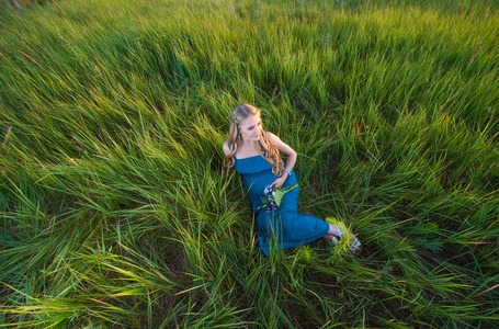 美丽的孕妇躺在绿色的草地上