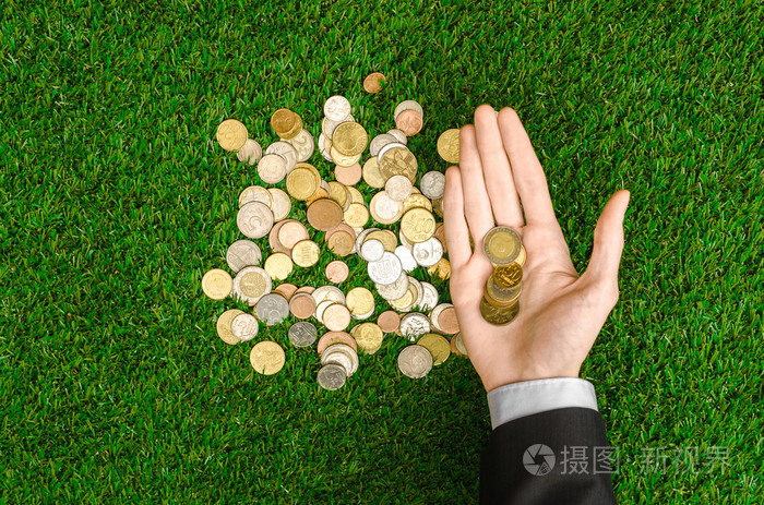 金钱和财务主题: 钱硬币和人的手在显示手势的绿色背景上的黑色西装草