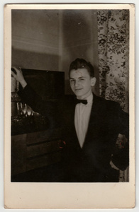 一张老式照片显示年轻男孩穿夹克和蝴蝶结。