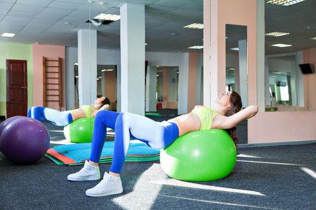 普拉提的女人侧弯曲 fitball 锻炼锻炼在健身房室内瑞士球