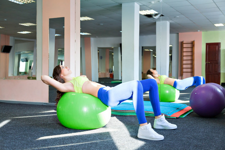 普拉提的女人侧弯曲 fitball 锻炼锻炼在健身房室内瑞士球