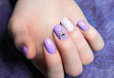 美丽的紫色指甲油,用晶体在女性手上.特写照片