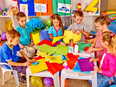孩子们在幼儿园里拿着彩纸上工艺课。
