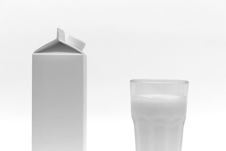 白色的空牛奶盒和一杯牛奶，在白色背景上
