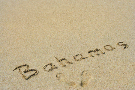 院手中的或手写的巴哈马文本在异国岛海滩上的沙子