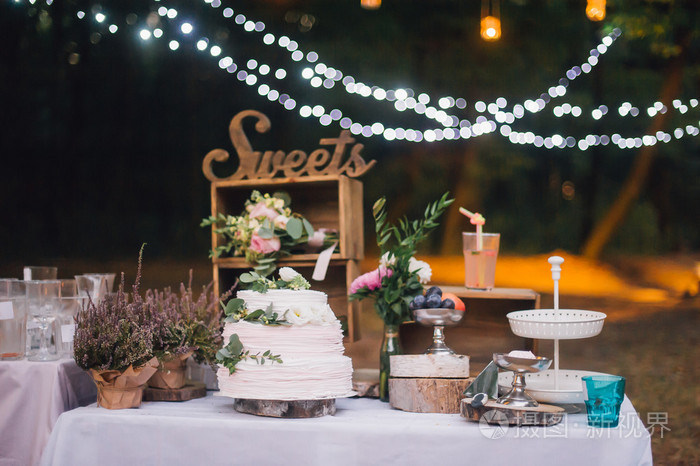 多层白色婚礼蛋糕站在桌子上，上面有花饰
