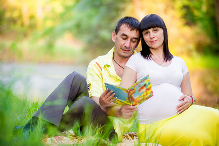 快乐怀孕的妇女和她的丈夫在公园