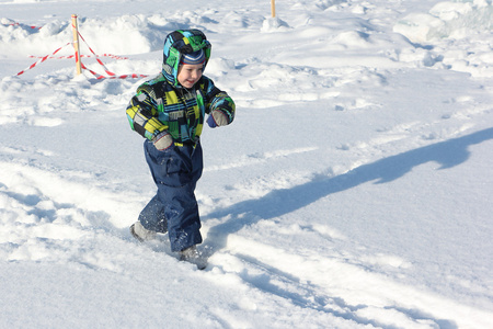 孩子在冬天在雪地上奔跑的颜色夹克