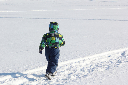 孩子在冬天在雪地上奔跑的颜色夹克