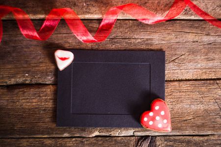 礼品卡上木制背景与心和红丝带形状的饼干