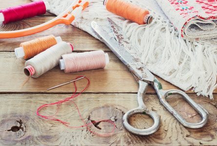 剪刀，纱的线和针，条纹织物。老木背景上的旧缝纫工具。复古背景