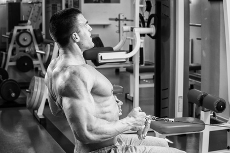 强壮的肌肉男在健身房里锻炼。在黑白照片上美丽的身体。健康的生活方式