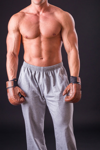 拳击手套上一个黑暗的背景中的肌肉男。职业拳击手拳击显示肌肉在机架上。美丽的肌肉发达的身体拳击手。体育杂志 海报和网站的照片