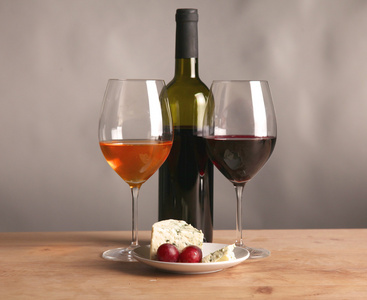 精制的静物画的酒 奶酪和葡萄在柳条托盘木制的桌子上