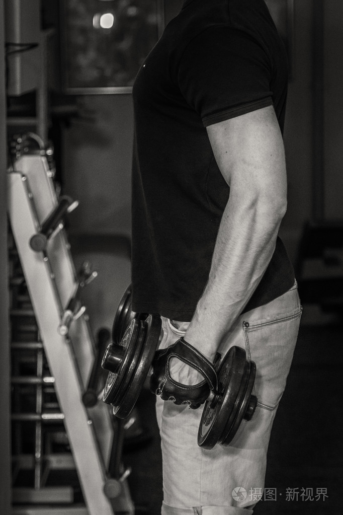 健美运动员使得用哑铃在健身房锻炼.手上的工作告诉肌肉.