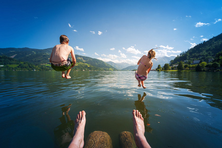 女孩和男孩在暑假在湖里的水跳
