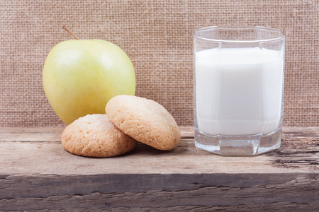 牛奶 苹果和饼干在木板上的玻璃