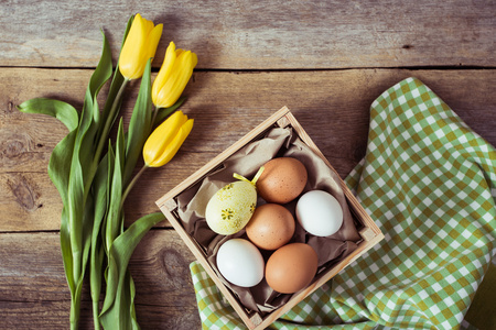 郁金香和木制背景上的鸡蛋。复活节背景
