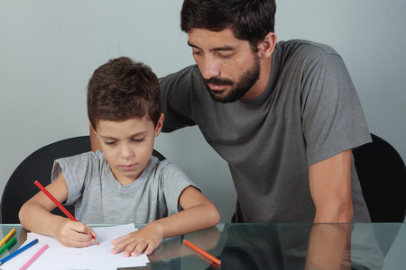 年轻的父亲和儿子在生活上用彩色铅笔绘图