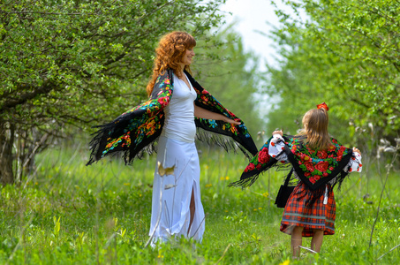 年轻美丽的母亲与她的女儿在花园里散步