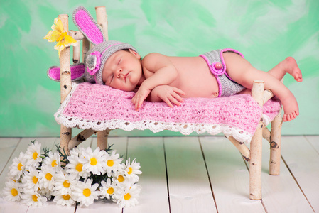 睡在木制婴儿床桦木针织的兔子服装初生女婴