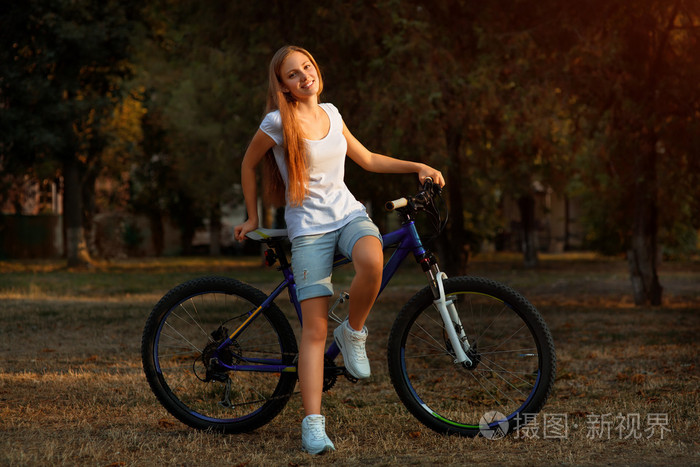 年轻可爱的女士骑着自行车在公园里摆姿势